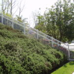 Closed-Picket-Perimeter-Pool-Style-White-vinyl-Fence-on-a-slope